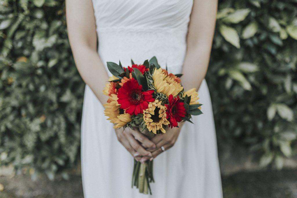 A bride stands with her bouquet at Coltsford Mill on her wedding day in the summer months