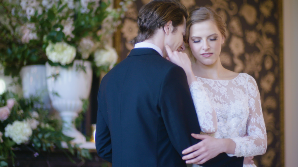 n elegant bride and groom embrace infront of some slowers at a wedding venue