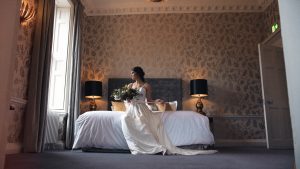 A bride sits on the endge of her bed looking out the window