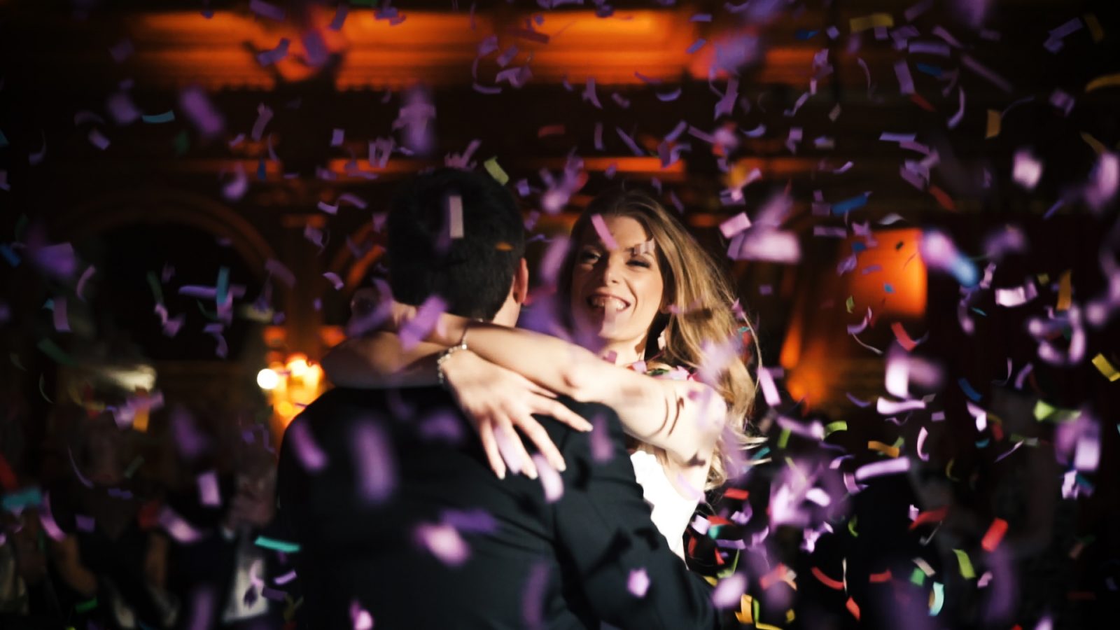 A Bride holds her groom as confetti falls around them