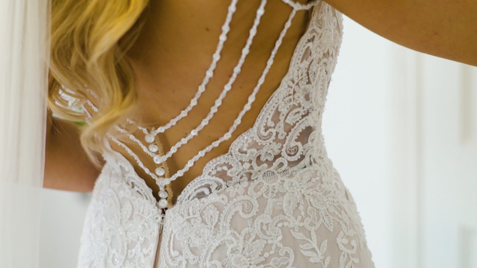 Detailing on the back of a wedding dress worn by a bride