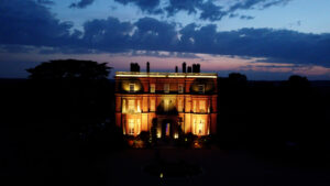 Hedsor House shot from a drone showing the house from the front view with a red and blue sky behind