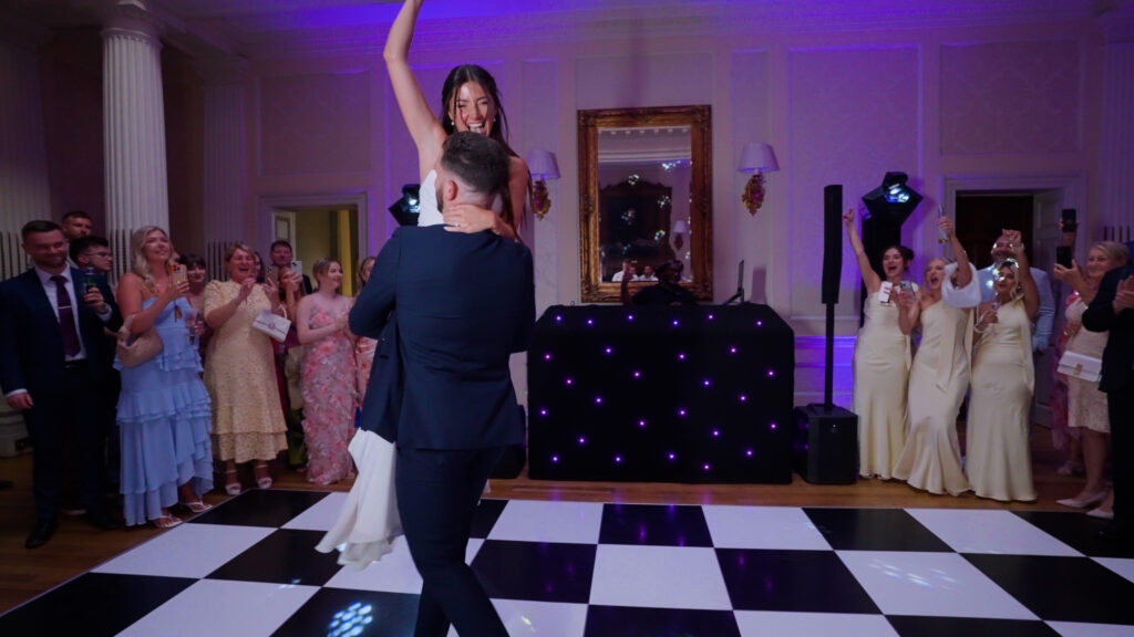 A groom lifts his bride high during their first dance